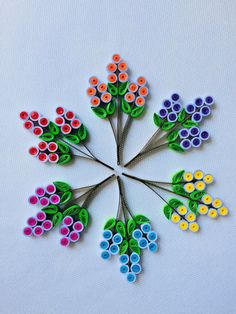 a group of colorful flowers made out of rolled up paper on a white table top