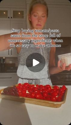 a woman standing in front of a tray filled with tomatoes and ketchup on top of a counter