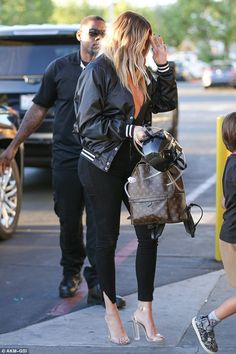 the blonde woman is talking on her cell phone while walking down the street with two other people