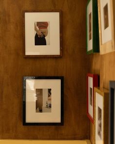 three framed pictures hang on the wall above a bench in a room with wood paneling