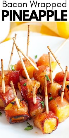 bacon wrapped pineapple bites on a white plate with toothpicks in the middle