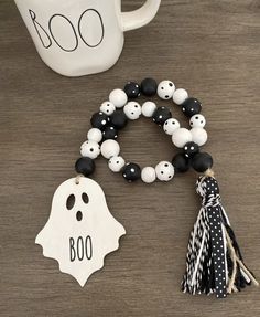 two bracelets with black and white beads are on a table next to a mug