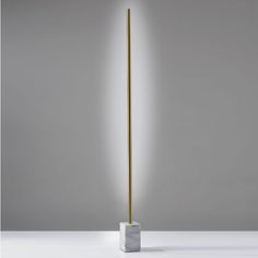 a floor lamp with a marble base and a gold metal pole on the top, against a gray background