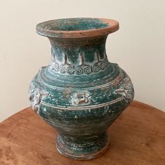 a green vase sitting on top of a wooden table