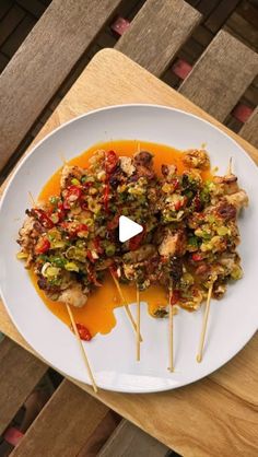 a white plate topped with meat and veggies on skewered toothpicks