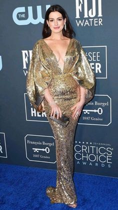 an image of a woman in gold dress at the blue carpet awards event with her hand on her hip