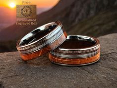 two men's wedding bands sitting on top of a rock with the sun setting in the background