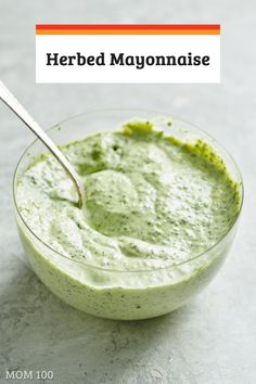 a bowl filled with green sauce on top of a table next to a spoon and the words herb mayonnaise above it