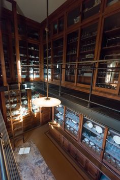 a room filled with lots of wooden shelves and glass cases full of dishes on top of them