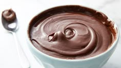 a white bowl filled with chocolate frosting next to a spoon