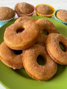 a green plate topped with donuts next to cupcakes