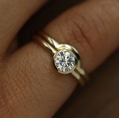 a woman's hand with two gold rings and a diamond