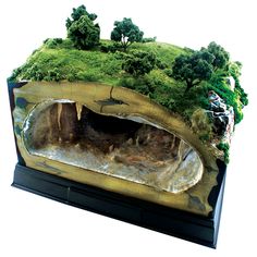 a model of an area with trees and rocks on it's sides, in the shape of a cave