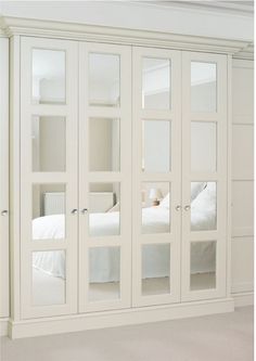 a white bedroom with mirrored doors on the wall