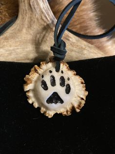 a dog's paw print is on the front of a necklace that hangs from a black cord