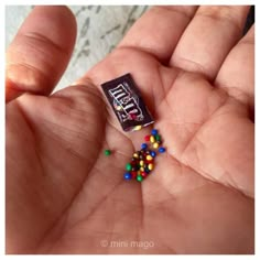 a hand holding a candy bar with multicolored candies on it's palm