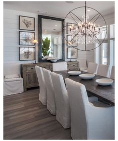 a dining room table with white chairs and a chandelier