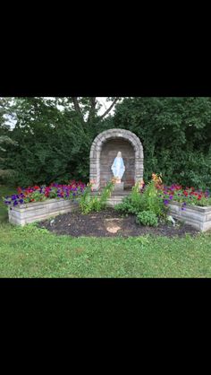 a garden with flowers and a statue in the middle