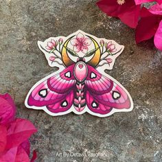 a pink butterfly sticker sitting on top of a stone floor next to some flowers