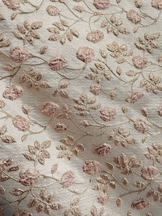 an embroidered fabric with pink flowers and leaves on white background, closeup shot from the neck down