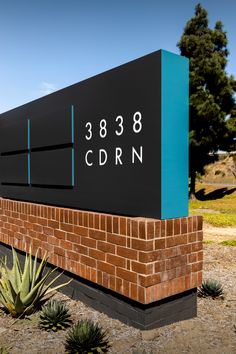 the sign for cbrn is shown in front of some cactuses and trees on a sunny day