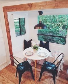 a small table with two black chairs and a white table in front of a window