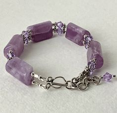 This beautiful lavender quartz bracelet is very elegant ! The five quartz sections are separated by a double row of sterling silver flower spacers, round sterling beads and 6mm violet Swarovski Bicone crystals. They offer a little sparkle against the translucence of the quartz. The bracelet closes with a hook clasp and has a 2 inch chain extender ending in a Swarovski Crystal for a finished appearance. This bracelet is a statement piece that will make a wonderful addition to your jewelry collect Elegant Lavender Beaded Bracelets With Faceted Beads, Elegant Lavender Beaded Bracelet With Faceted Beads, Elegant Lavender Bracelets With Faceted Beads, Elegant Lavender Beaded Bracelets With Gemstone, Elegant Lavender Gemstone Beaded Bracelets, Elegant Handmade Lavender Crystal Bracelet, Elegant Lavender Beaded Bracelet For Healing, Lavender Gemstone Beaded Bracelets For Jewelry Making, Adjustable Lavender Gemstone Beads Bracelets