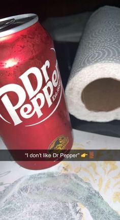 a can of soda sitting on top of a table next to a roll of paper