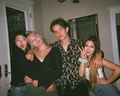 four young people posing for the camera in front of a door with their arms around each other