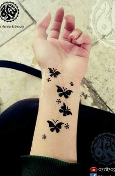 a woman's wrist with black butterflies on it