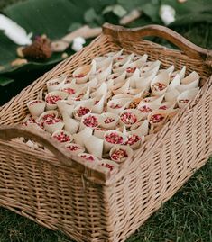 a wicker basket filled with food sitting on top of a lush green field next to leaves