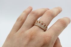 a woman's hand with a gold crown ring on top of her left hand