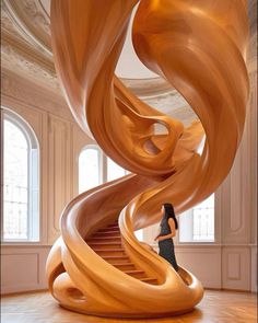 a woman is standing in front of a spiral wooden staircase that looks like it has been carved