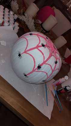 a large white ball covered in spider webs on top of a wooden table next to candles