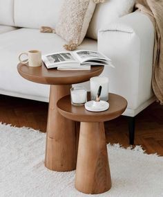 a coffee table with magazines and candles on it in front of a white couch,