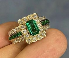 an emerald and diamond ring on someone's finger