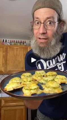 a bearded man holding a tray of food in his hands and looking surprised at the camera