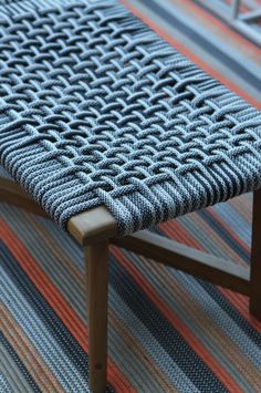 a wooden bench sitting on top of a colorful rug next to a chair with an armrest