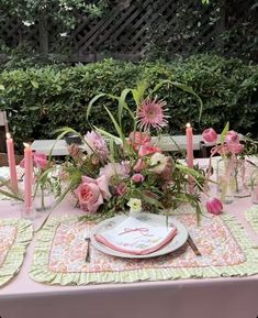 the table is set with pink flowers and candles