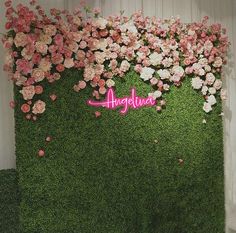 an artificial wall with pink and white flowers in the center is surrounded by green grass