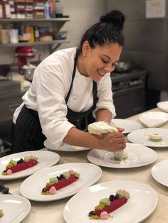 a woman in an apron is decorating plates with desserts on the kitchen counter