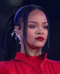 a close up of a person with long hair and earrings on her head, wearing a red shirt