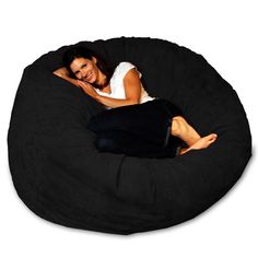 a woman laying on top of a black bean bag chair