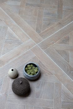 a bowl full of green apples sitting next to a ceramic object on the floor in front of it