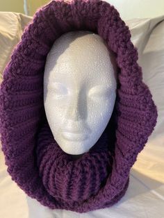 a white mannequin head wearing a purple knitted cowl hat and scarf