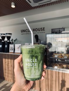 a person holding up a green drink in front of a counter