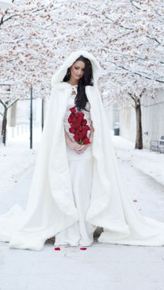 a woman wearing a white wedding gown with red roses in her hand