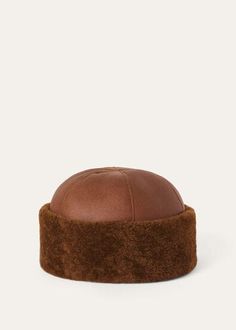 a brown leather hat on a white background, with the top part of it covered in fur