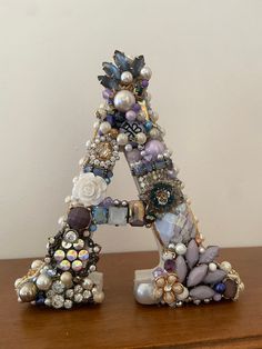 the letter is made out of beads and other things on top of a wooden table