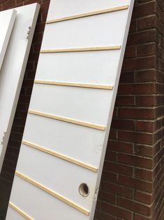 two white doors with wooden slats in front of a brick wall and one closed